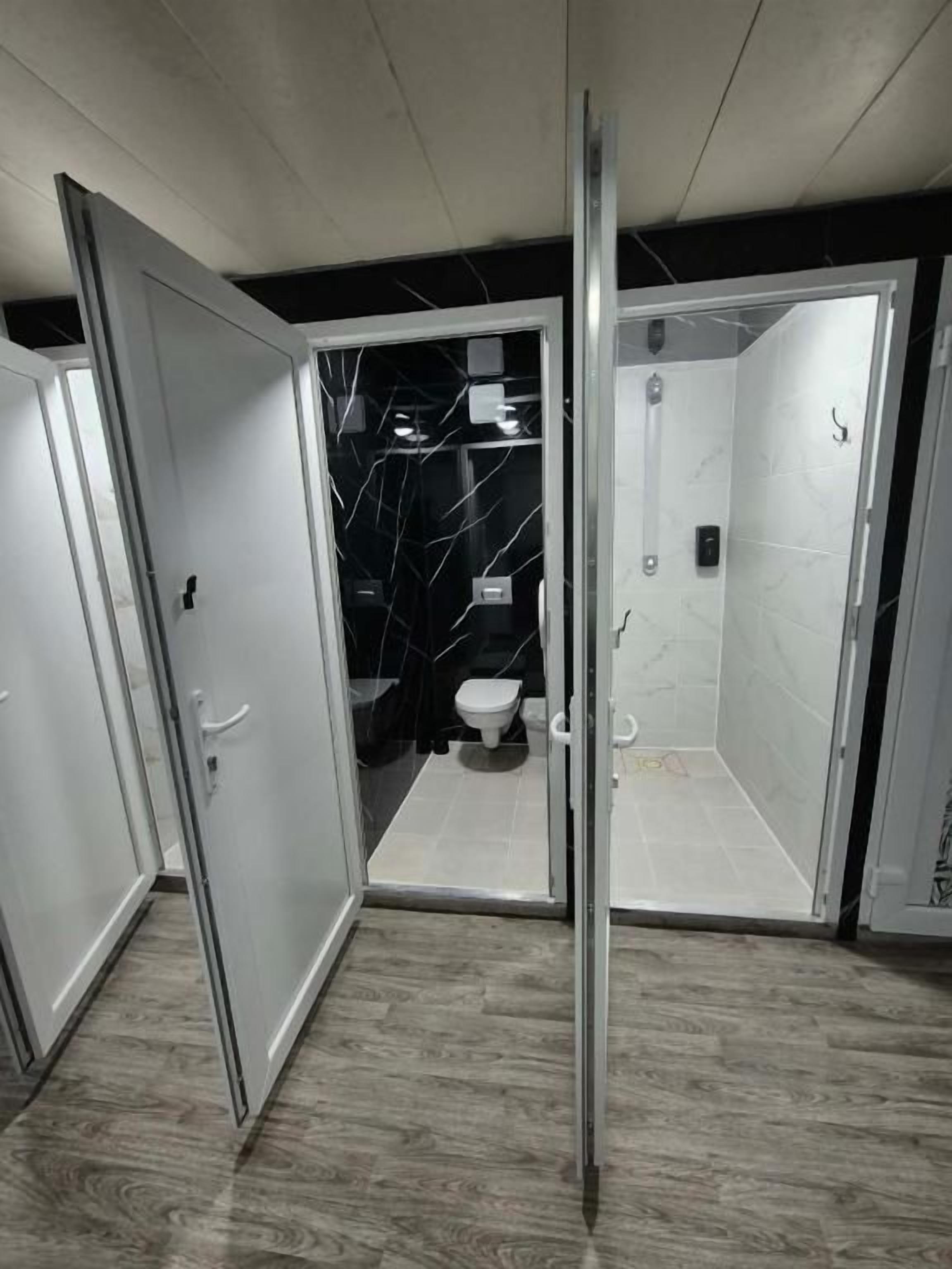 Casa de banho moderna com divisória de vidro, sanita e zona de duche.