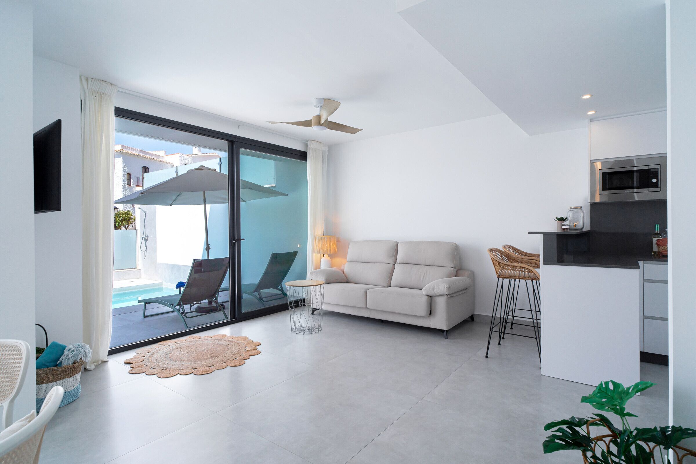 A modern living room with a sofa, chairs, a small table, and a kitchen area with a microwave.