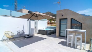 A modern outdoor patio with a hot tub, a seating area, and a glass-enclosed room. - Villa Casa Mezcal by Casasol (Nerja)