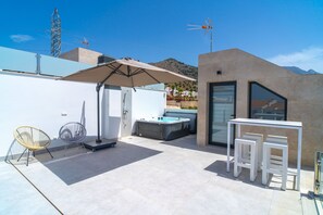 A modern outdoor patio with a hot tub, a seating area, and a glass-enclosed room. - Villa Casa Mezcal by Casasol (Nerja)