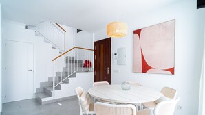 A modern interior with a staircase, a dining area with white furniture, and a large abstract painting. - Villa Casa Mezcal by Casasol (Nerja)