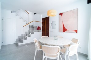 A modern interior with a staircase, a dining area with white furniture, and a large abstract painting. - Villa Casa Mezcal by Casasol (Nerja)