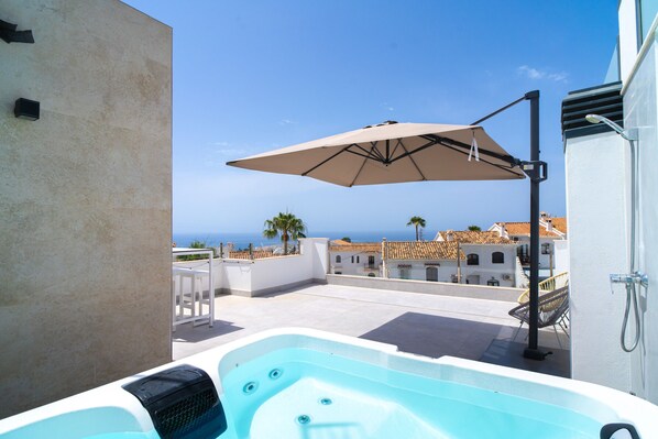 A rooftop terrace with a hot tub, an umbrella, and a view of the sea and buildings. - Villa Casa Mezcal by Casasol (Nerja)