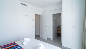 A hotel room with a bed, a ceiling fan, a bathroom with a mirror, and a wardrobe. - Villa Casa Mezcal by Casasol (Nerja)