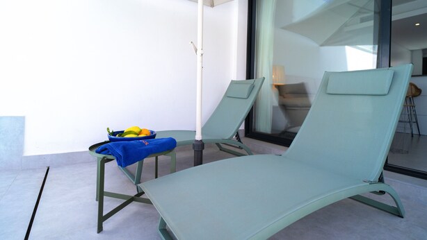 A balcony with two lounge chairs, a table with a blue towel, and a basket of fruits. - Villa Casa Mezcal by Casasol (Nerja)