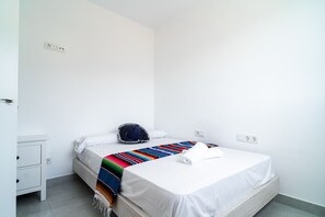 Ein Einzelzimmer mit einem weißen Bett, einer farbenfrohen Decke, einem Sombrero und einem weißen Handtuch.