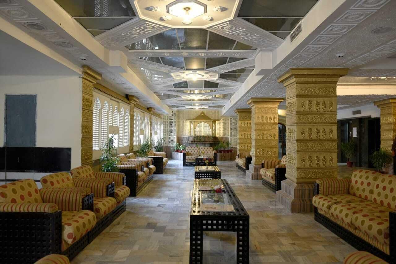 A spacious lobby with patterned sofas, a central coffee table, and decorative columns.