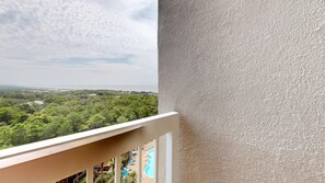 A balcony with a view of a lush green landscape and a distant body of water. - Summit 908/908A Luxury Gulf-View Escape | TOPS'L Resort | Walk to the Beach (Miramar Beach)