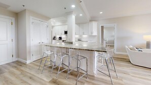 A modern kitchen with a central island, bar stools, and white cabinetry. - Summit 908/908A Luxury Gulf-View Escape | TOPS'L Resort | Walk to the Beach (Miramar Beach)