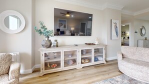 A living room with a white console table, a round mirror, and a framed artwork on the wall. - Summit 908/908A Luxury Gulf-View Escape | TOPS'L Resort | Walk to the Beach (Miramar Beach)
