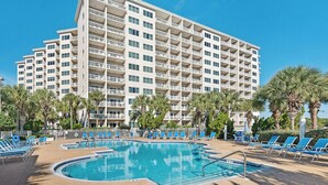 Un hotel con varias plantas, piscina y palmeras.