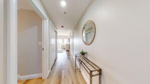 A hallway with a wooden floor, a mirror on the wall, and a console table with a plant. - Summit 0908A Romantic Gulf-View Studio at TOPS'L Resort (Miramar Beach)
