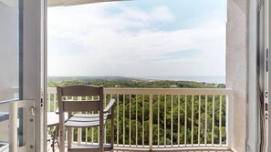 A balcony with a chair and a table, overlooking a landscape with trees and a distant view. - Summit 0908A Romantic Gulf-View Studio at TOPS'L Resort (Miramar Beach)