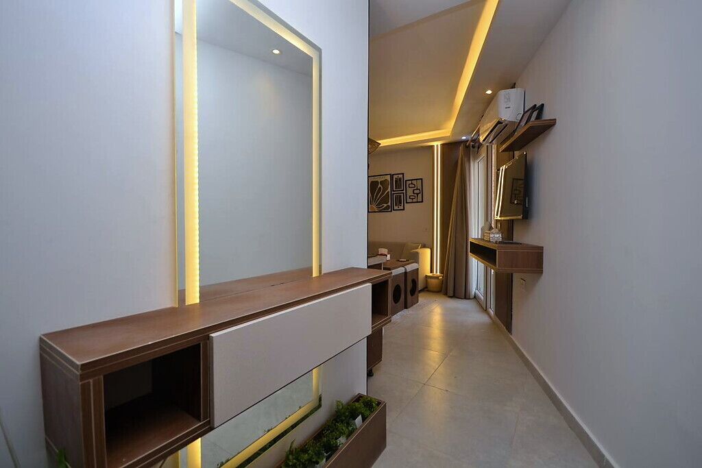 Een moderne gang met een houten console, een spiegel en een televisie aan de wand.