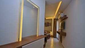 Un pasillo con un banco de madera, un televisor de pared y una puerta con iluminación.