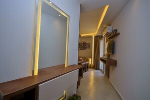 Ein Flur mit einer hölzernen Bank, einem an der Wand montierten Fernseher und einer Tür mit Lichtleiste.
