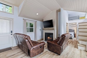 A living room with two leather recliners, a fireplace, a flat-screen TV, and a door with an 'Authorized Personnel Only' sign. - Tiny Home, HUGE Views, Massive Deck + Fire pit (Blairsville)