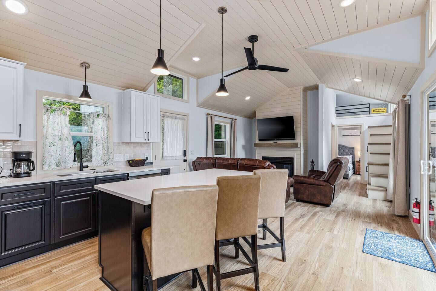 A modern kitchen with a large island, dark cabinetry, and pendant lighting.