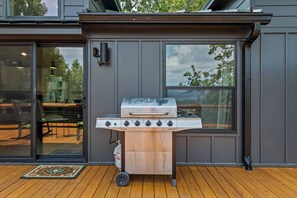 An outdoor grill on a wooden deck with a sliding glass door leading to an indoor dining area. - Tiny Home, HUGE Views, Massive Deck + Fire pit (Blairsville)