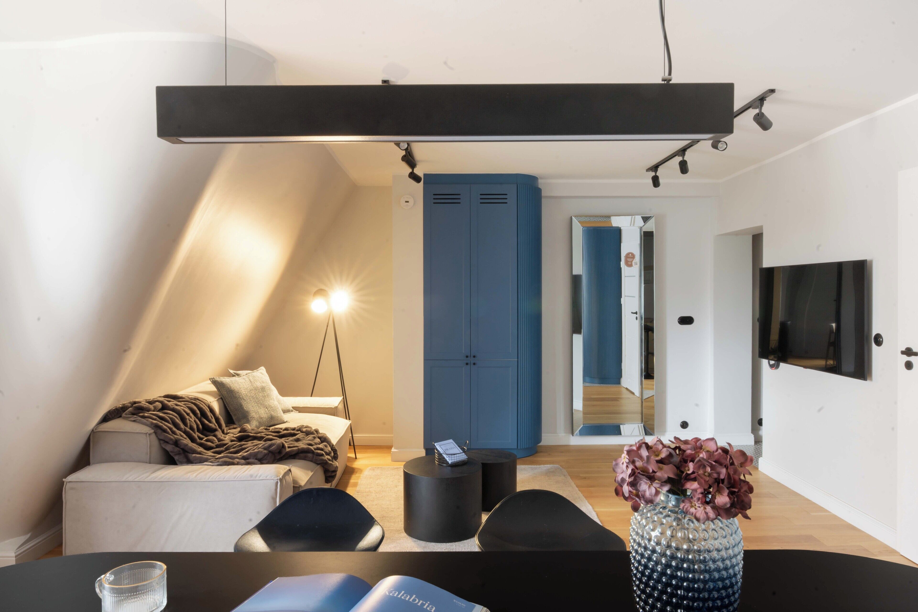 A modern living room with a sofa, a coffee table, and a TV mounted on the wall.