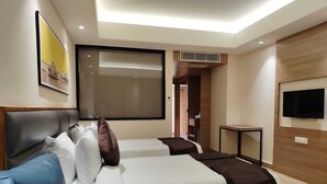 A hotel room with a bed, a blue sofa, a television, and a large window.