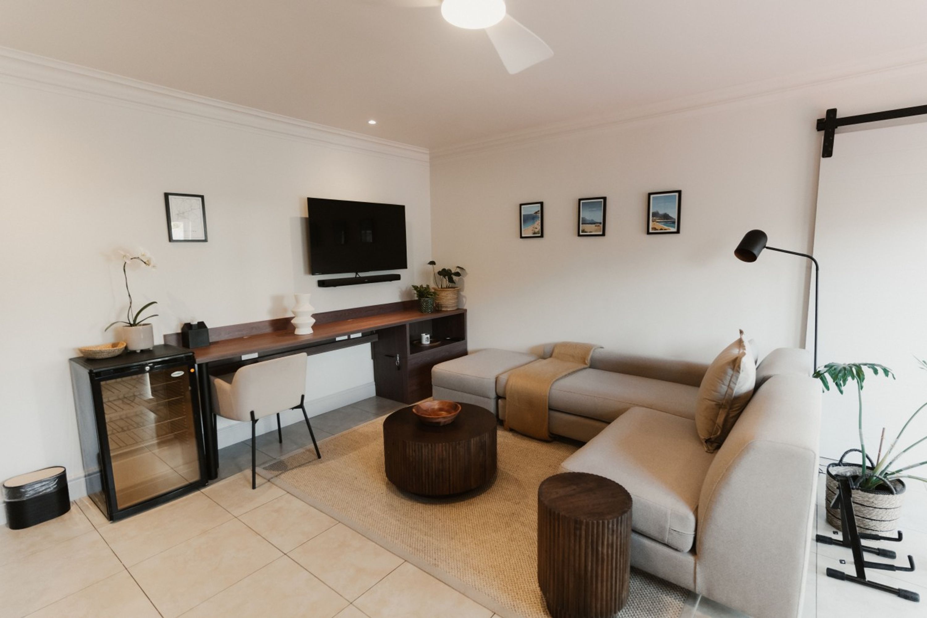 Un salon moderne avec un canapé, une table basse et un téléviseur à écran plat fixé au mur.