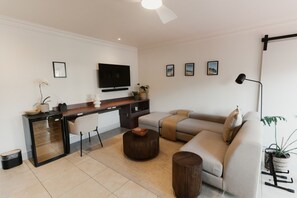 Ein modernes Wohnzimmer mit einer Couch, einem Couchtisch und einem an der Wand befestigten Flachbildfernseher.