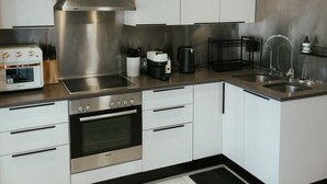 Een moderne keuken met roestvrijstalen apparatuur, witte kasten en een zwart aanrecht.