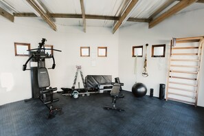 Ein Fitnessraum mit Trainingsgeräten, einer Klimmzugstange und einer Kettlebell.
