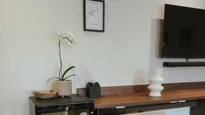 Een kitchenette met een koelkast, een spoelbak en een aanrecht. Op het aanrecht staat een stoel en een potplant.