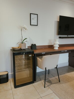 A kitchenette with a refrigerator, a sink, and a countertop. There is a chair and a potted plant on the countertop. - One Bed Apt Modern Cozy Secure Sea Point (Cape Town)