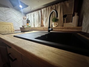 A kitchen with a black sink, wooden countertop, and a modern faucet. - Ferienwohnung in Kempten – Terrasse & Allgäu (Kempten (Allgäu))