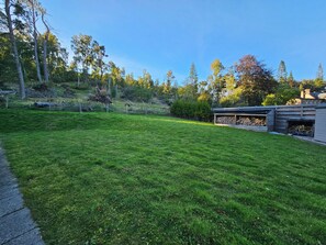 Ein gepflegter Rasen mit einer Holzterrasse und einem Gartenhaus.