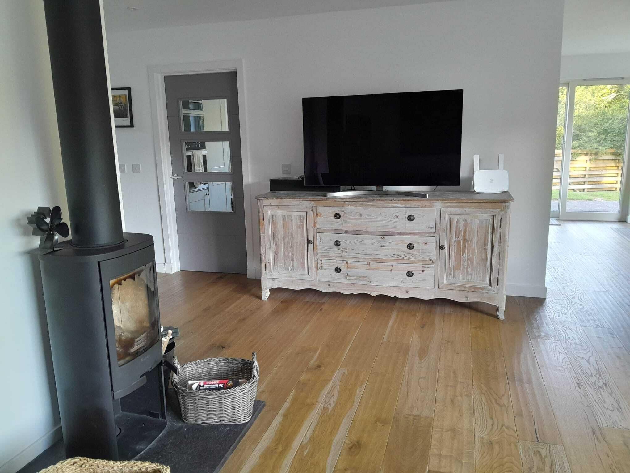 A living room with a wood-burning stove, a television on a cabinet, and a basket on the floor.
