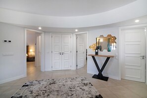 A modern interior with white walls, a central hallway, and a roundabout seating area. - Beautiful 2-Bedroom Apartment with Private Pool and Garden in Quinta do Lago (Faro)