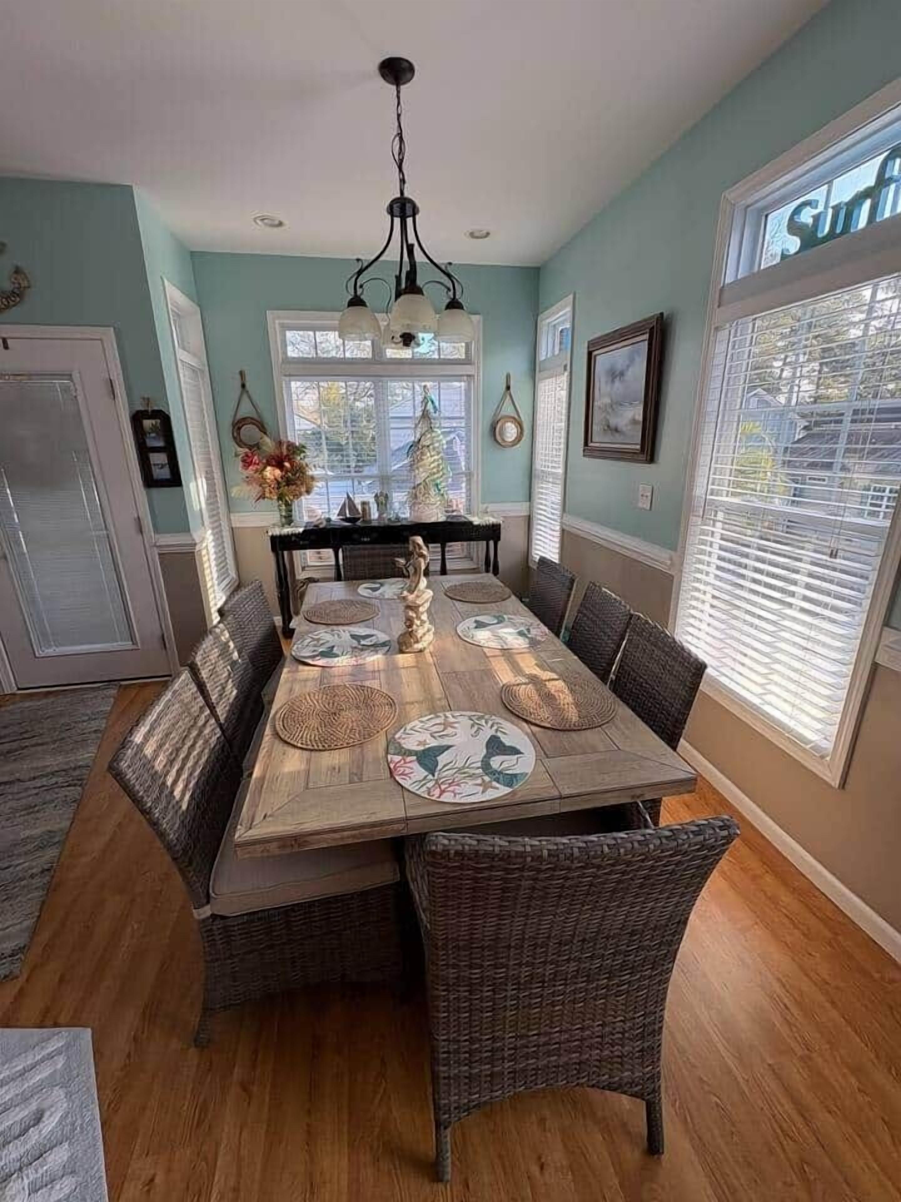 A dining room with a wooden table, wicker chairs, and a hanging light fixture.