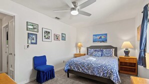 A bedroom with a bed, a chair, a ceiling fan, and a painting on the wall. - Resort Townhome with Private Patio near Beach (Panama City Beach)