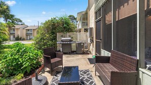 An outdoor patio with wicker furniture, a grill, and a water feature. - Resort Townhome with Private Patio near Beach (Panama City Beach)