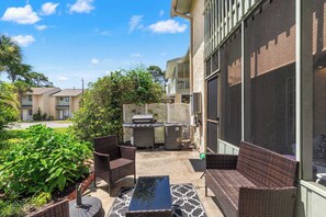 Eine Terrasse im Freien mit Korbmöbeln, einem Grill und einem Wasserspiel.