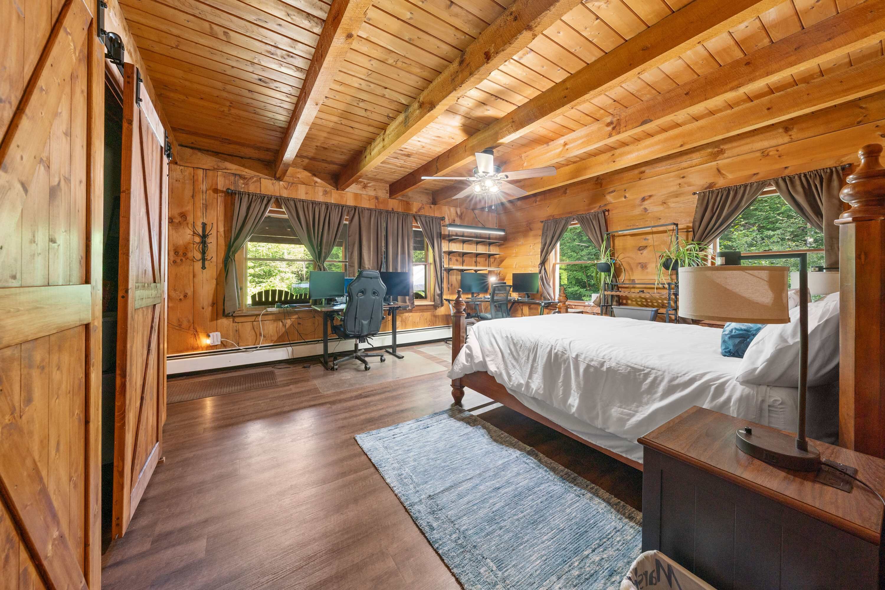 Un dormitorio de cabaña de madera con cama, escritorio y silla.