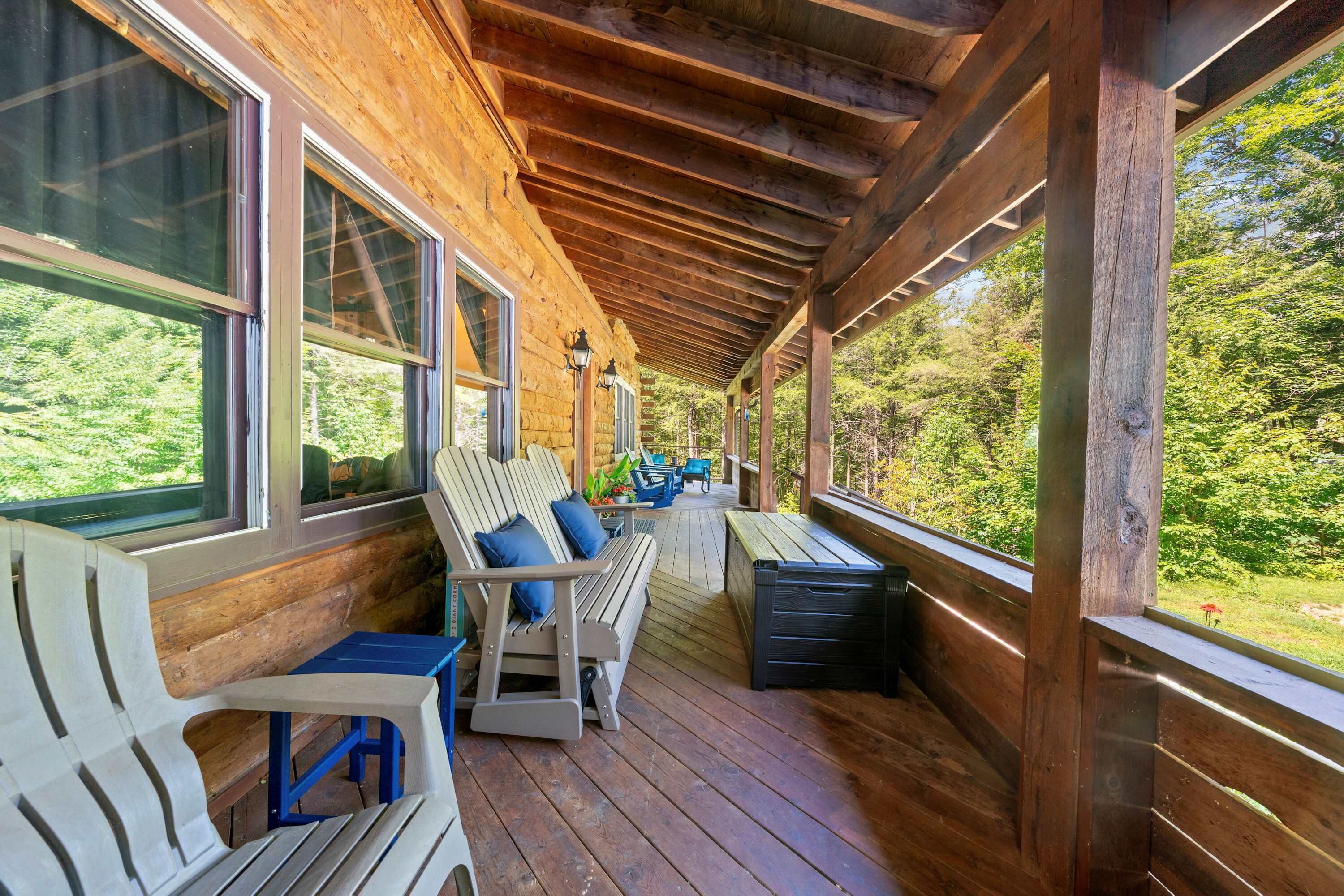 Une véranda couverte avec un plancher en bois, un banc et une table avec des chaises.