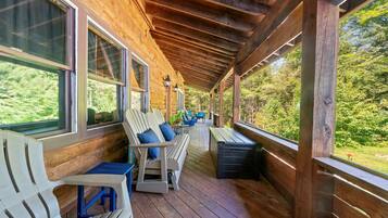 Une véranda couverte avec un plancher en bois, un banc et une table avec des chaises.