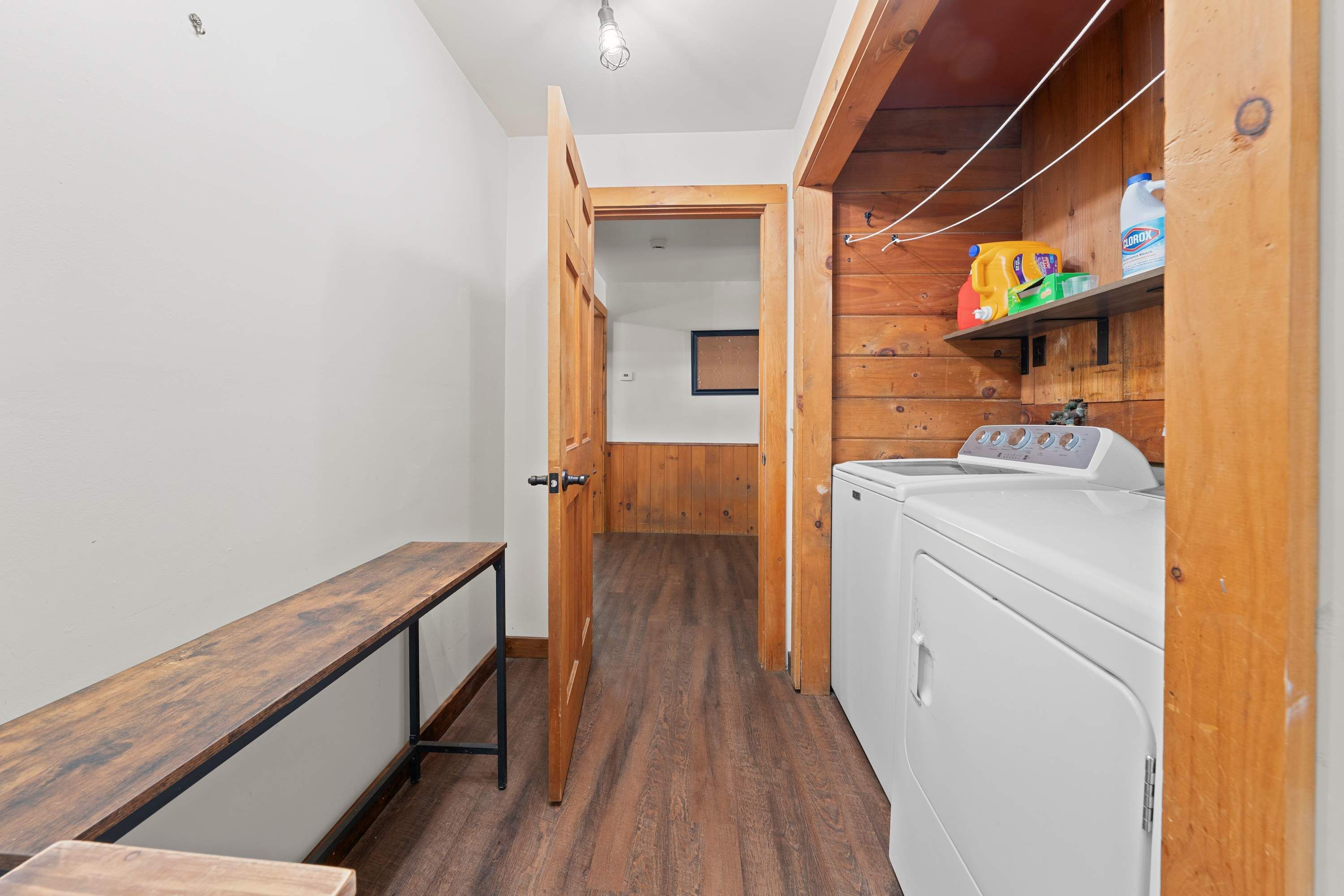 A laundry room with a washing machine, a bench, and wooden walls.