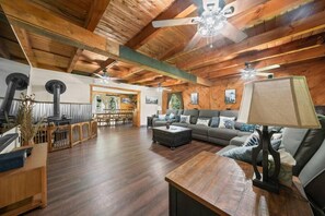 A spacious living area with a wooden ceiling, a sofa set, a coffee table, and a fireplace. - Riverfront Log Home - 28 Acres - Fire Pit (Warner)