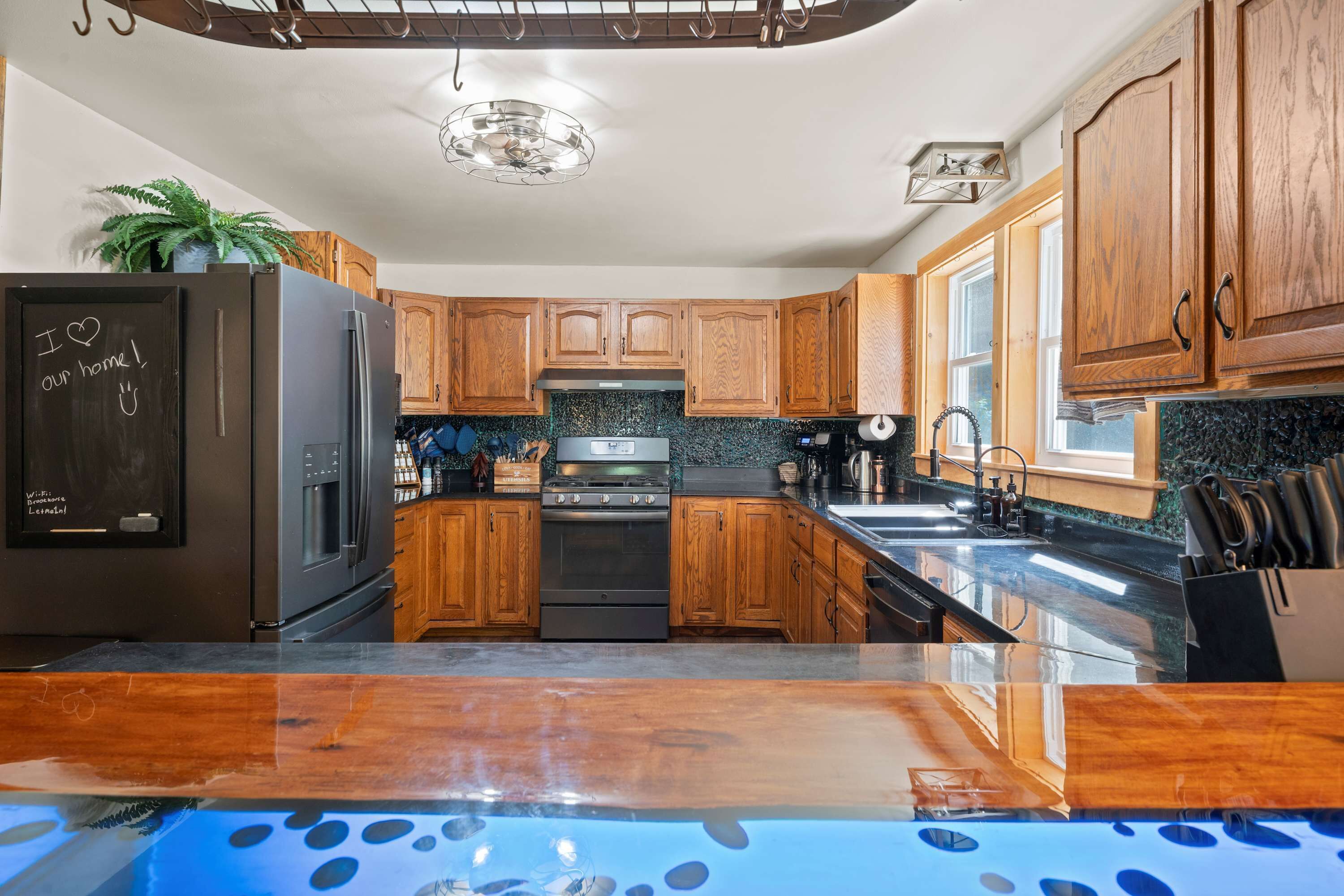 A modern kitchen with wooden cabinets, a stainless steel refrigerator, and a black stove.