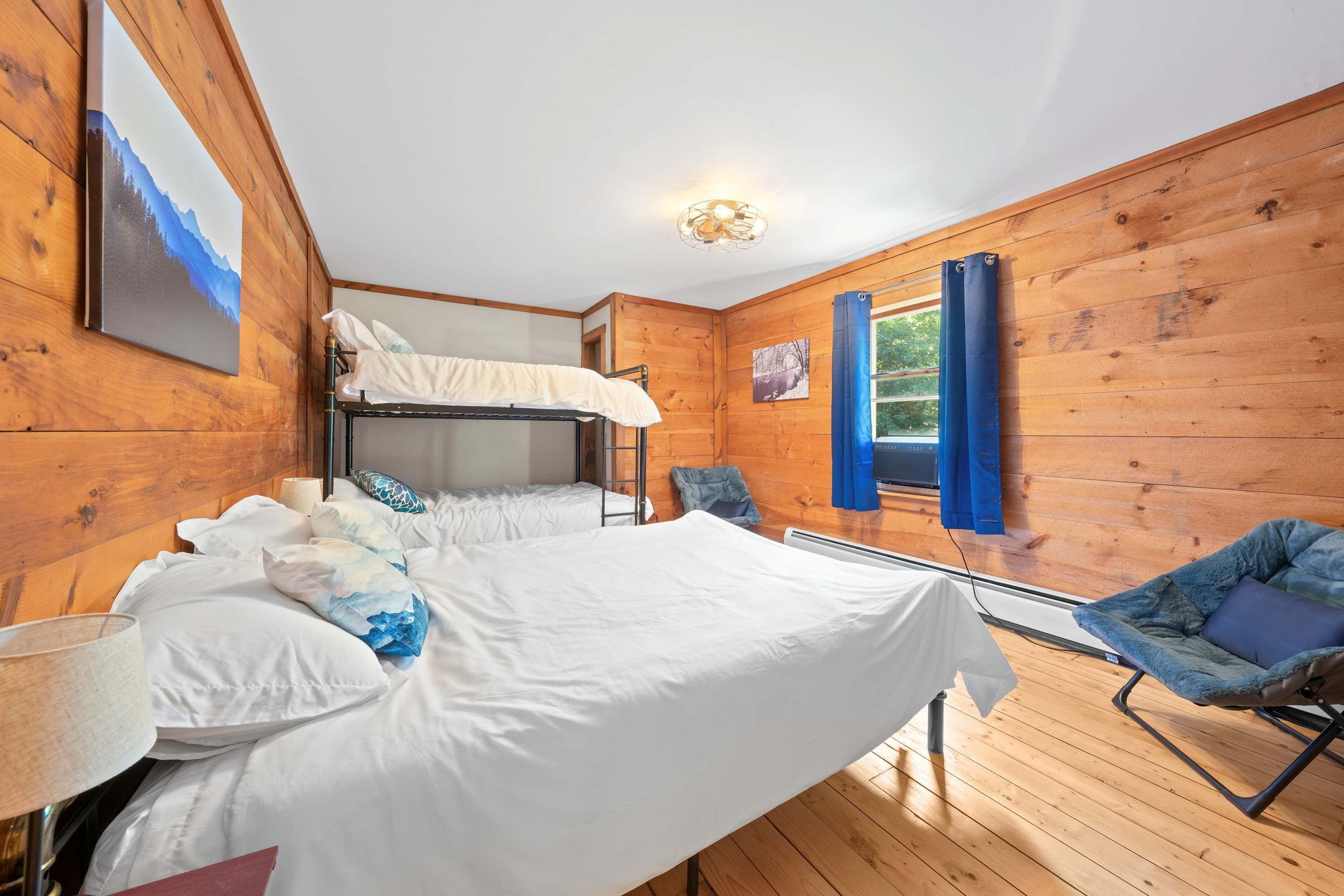 A wooden room with bunk beds, a desk, and a chair.