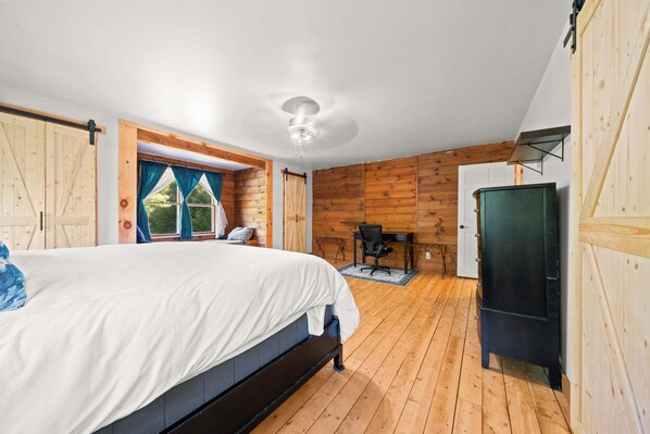 Een slaapkamer met een bed, een bureau en een kledingkast.
