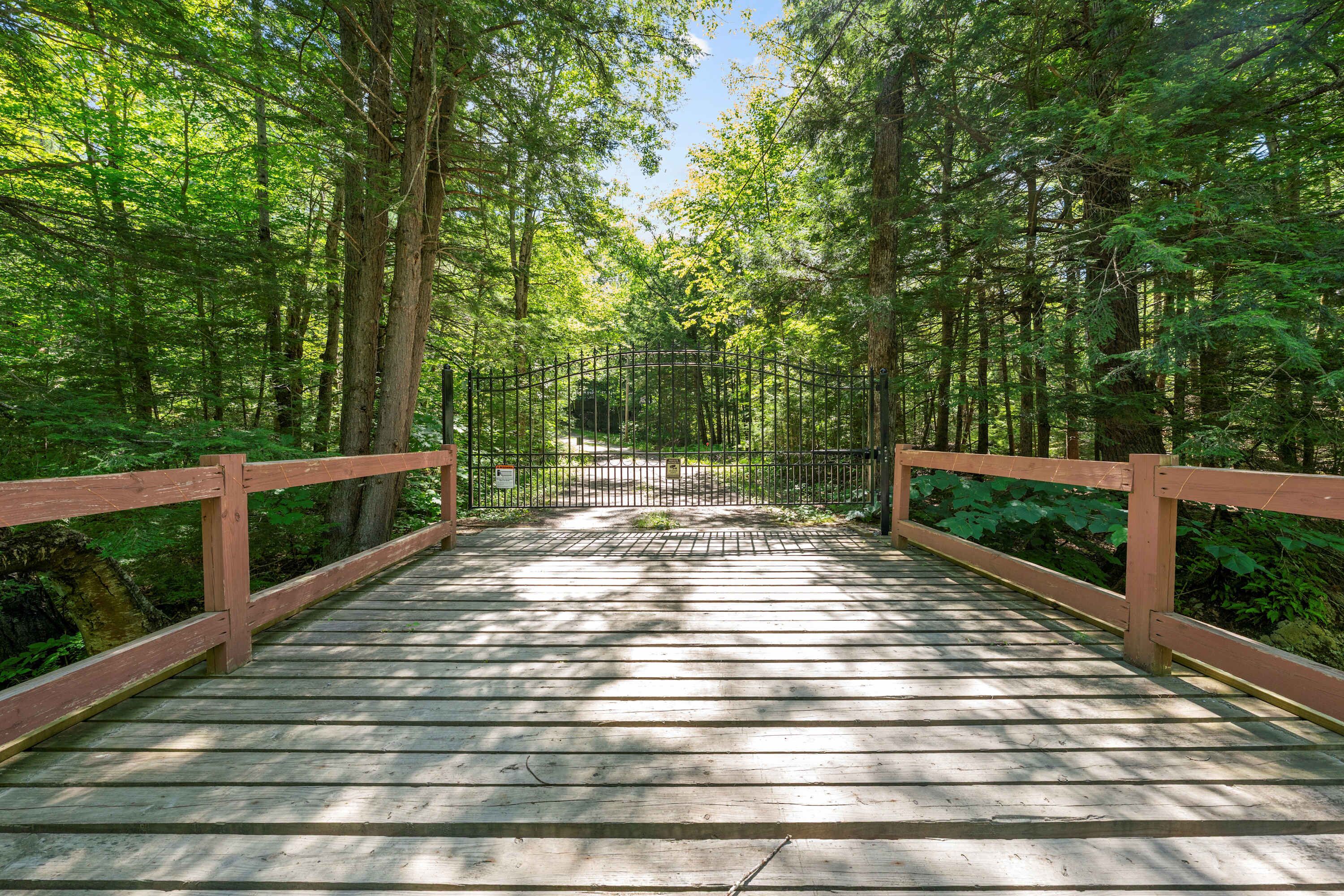 A wooden bridge with railings, surrounded by dense green foliage.