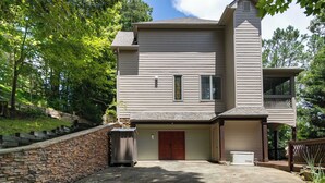 Ein zweistöckiges Haus mit Garage, einer Mauer aus Naturstein und einer Veranda.