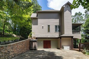 Ein zweistöckiges Haus mit Garage, einer Mauer aus Naturstein und einer Veranda.